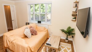 A bedroom with a bed, a TV, a small table, a potted plant, and a window with blinds. - 3 Rothbury Place (Lytham St. Anne's)