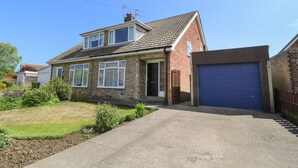 A two-story house with a garage, a front garden, and a clear blue sky. - 4 Ranby Drive (Hornsea)
