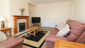 A living room with a fireplace, a television, a sofa, and a coffee table. - 4 Ranby Drive (Hornsea)