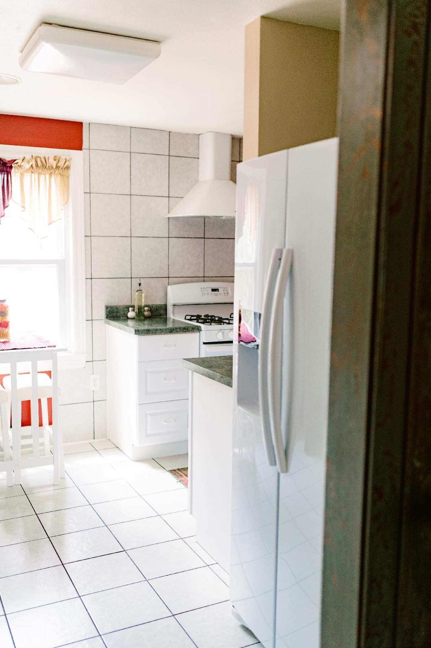 Een keuken met witte kastjes, een fornuis en een koelkast.