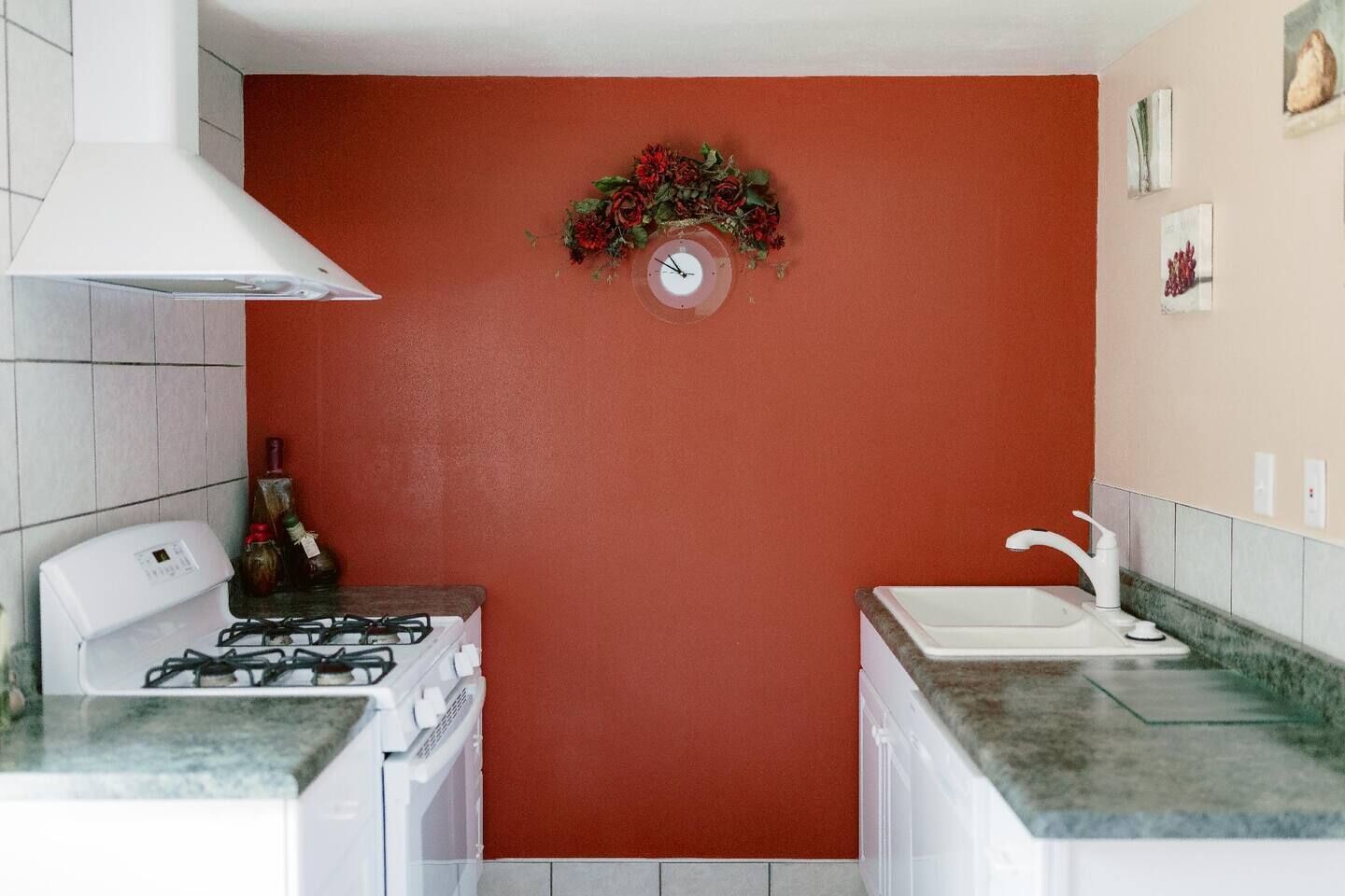 Una cocina compacta con estufa a gas, un lavamanos y un reloj de pared decorativo.