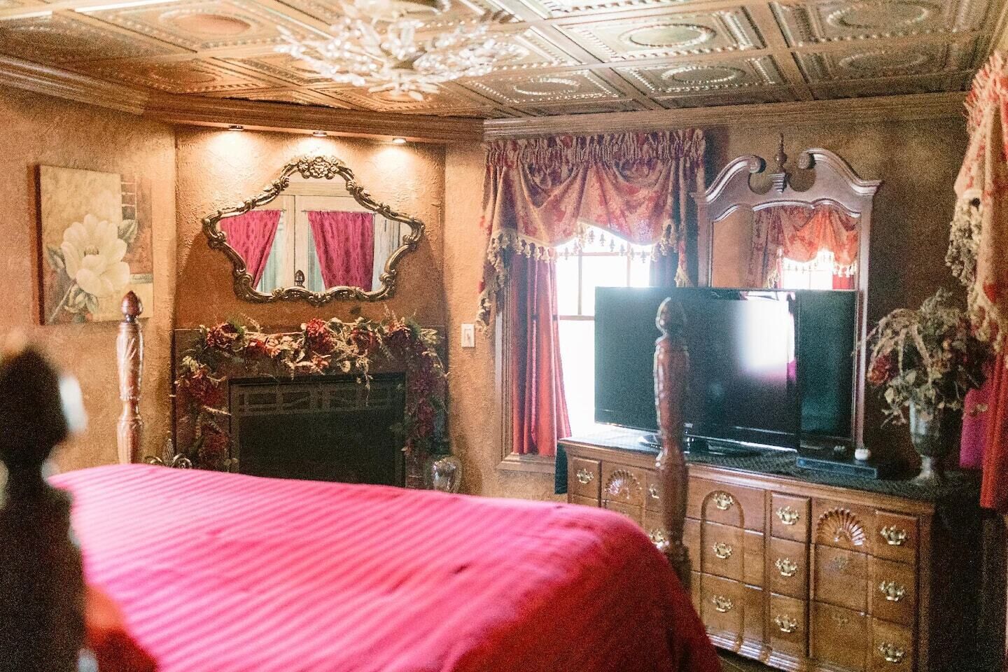 A bedroom with a large bed, a television, a dresser, and a mirror.