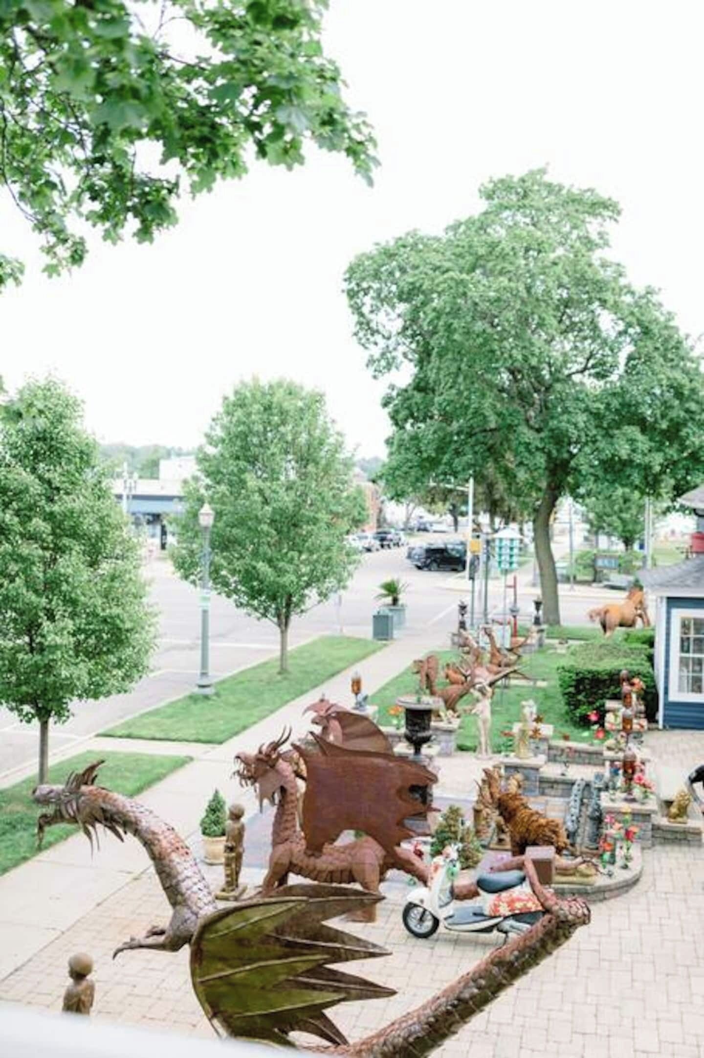 A park with a dragon statue, a carousel, and various sculptures.