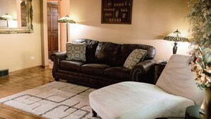 A living room with a brown leather sofa, patterned throw pillows, a light-colored armchair, a patterned area rug, and two floor lamps. - Top location, no cleaning fee, everthings close G (Lake Geneva)