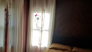 Makuuhuone, jossa on sänky, kattotuuletin ja verhot.