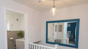 A modern bathroom with a toilet paper holder, a sink, and a mirror with a blue frame. - Dabbling Ducks (Whitby)