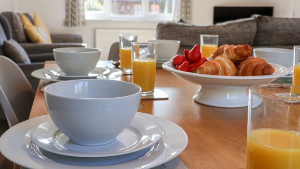 A breakfast setting with a bowl, croissants, and orange juice on a table. - Dabbling Ducks (Whitby)