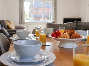 Un desayuno con un bol, croissants y zumo de naranja sobre una mesa.