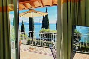 Un balcon donnant sur un lac, une pergola et une rambarde en métal.