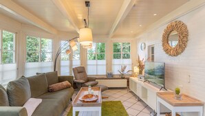 Una sala de estar con sofá, sillón, mesa de centro, televisor y objetos decorativos.