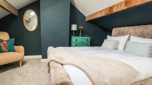 A bedroom with a large bed, a chair, a dresser, and a mirror on the wall. - No 19, Haworth (Keighley)