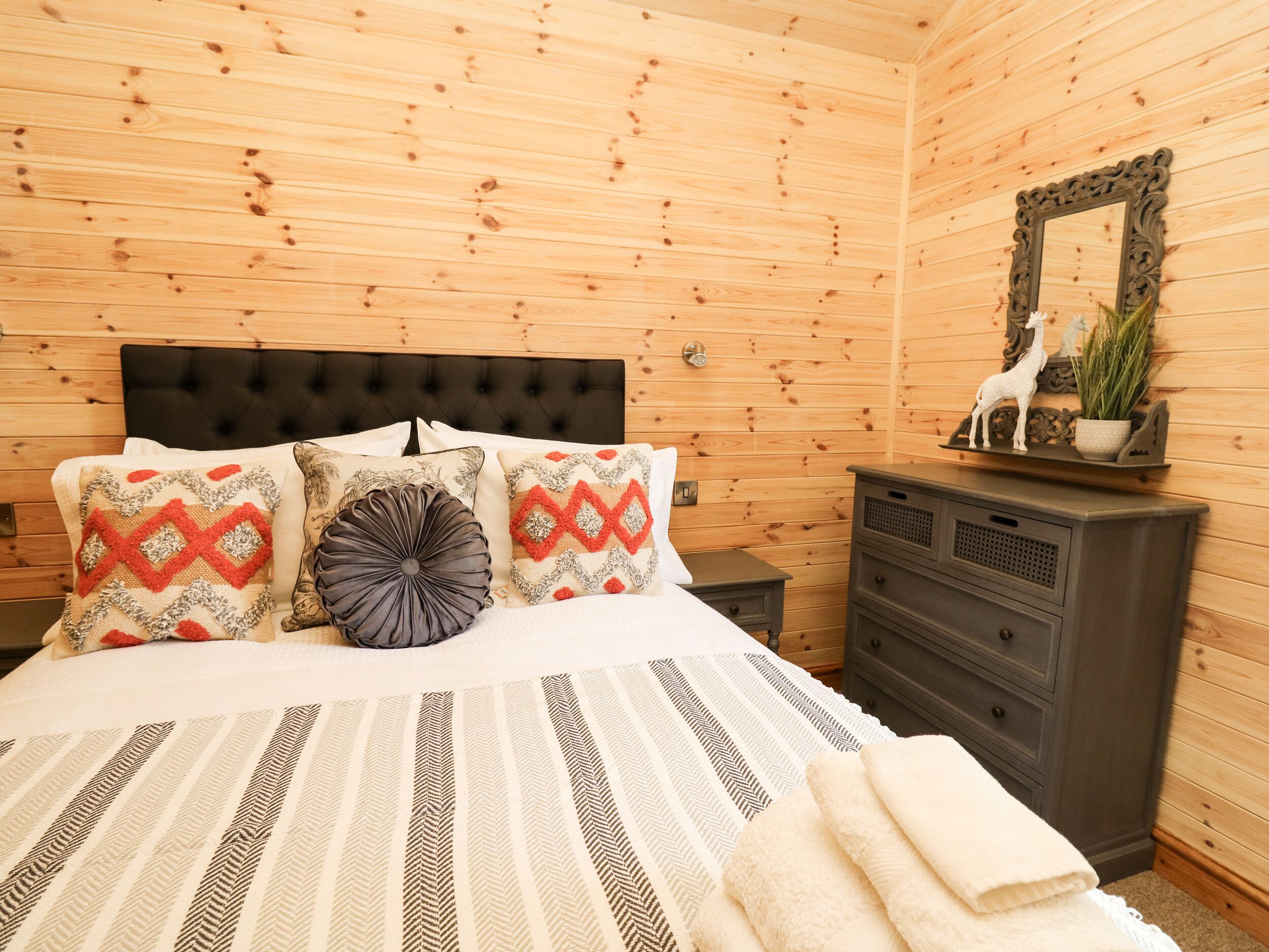 A wooden-paneled room with a bed, a dresser, and a mirror.