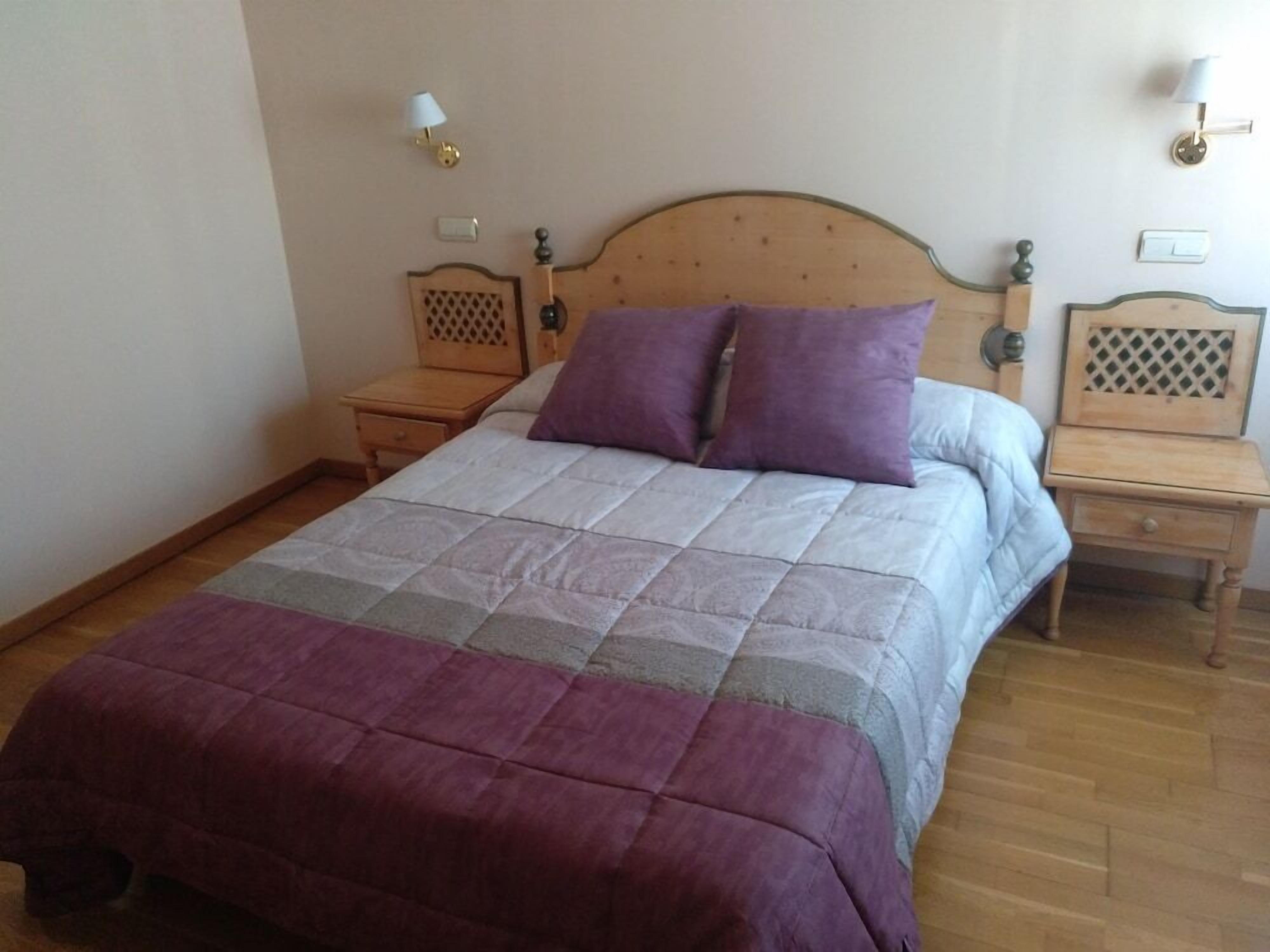 A bedroom with a wooden bed, two bedside tables, and a nightstand.
