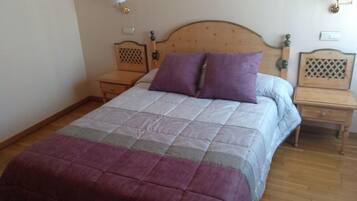 A bedroom with a wooden bed, two bedside tables, and a nightstand.