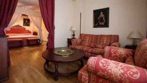 A room with a patterned sofa, a round coffee table, and a painting on the wall. - Hotel ELE Puerta de Monfrague (Malpartida de Plasencia)