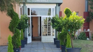 A building with a sign reading "SALONES" at the entrance, surrounded by potted plants. - Hotel ELE Puerta de Monfrague (Malpartida de Plasencia)
