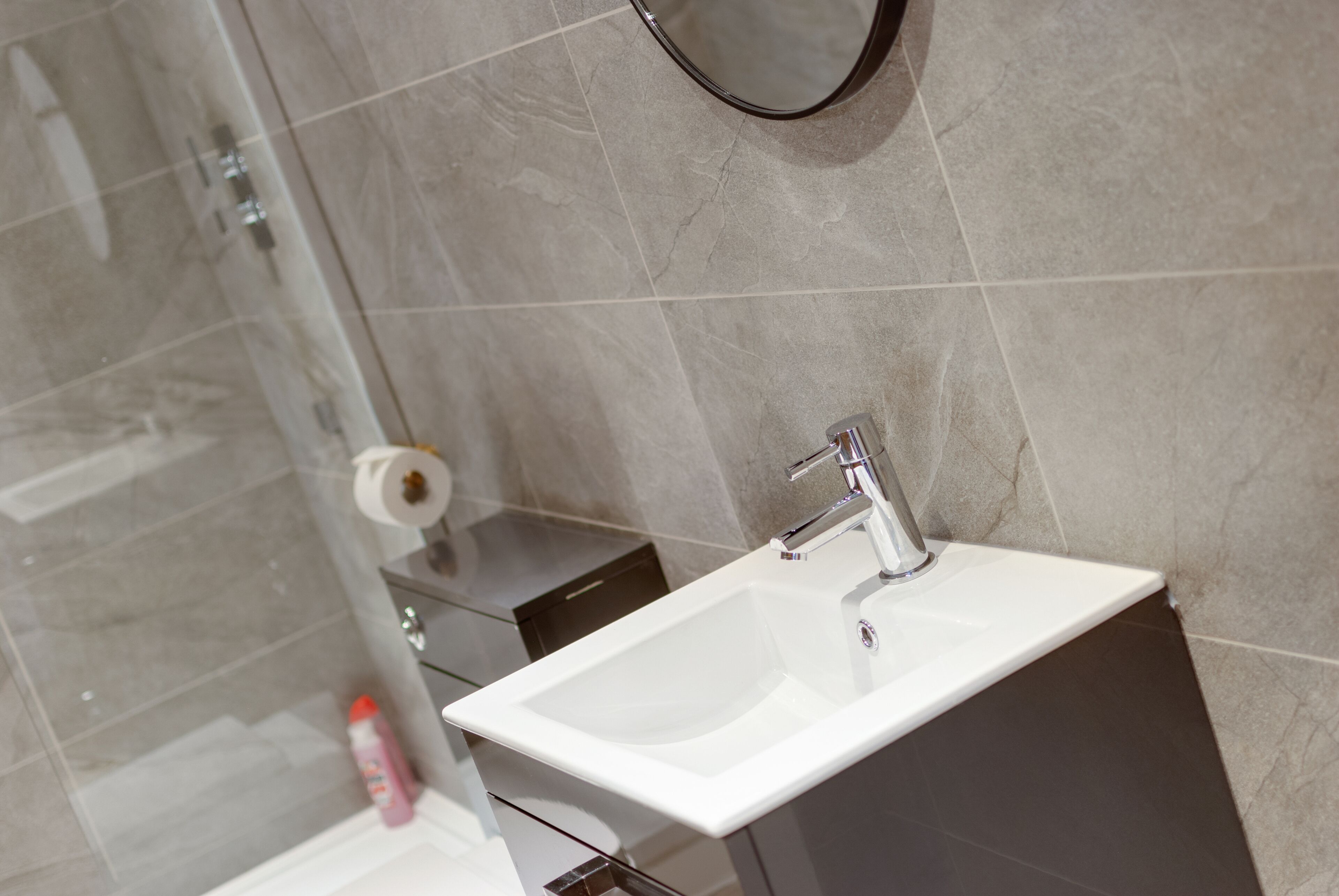 A bathroom with a white sink, a mirror, and a glass shower enclosure.