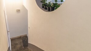 A staircase with a circular mirror on the wall, potted plants, and a light fixture. - 2 Apartments in Campo de Fiori with SPA and Jacuzzi (Roma)