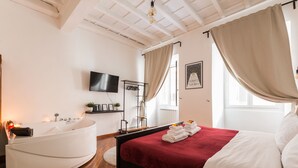 A bedroom with a large bed, a bathtub, a television, and a window with curtains. - 2 Apartments in Campo de Fiori with SPA and Jacuzzi (Roma)