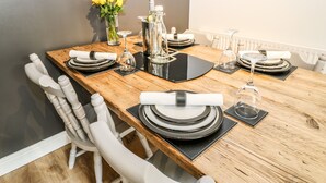 A dining table set with plates, glasses, and a vase of yellow flowers. - Victoria House (Holmfirth)