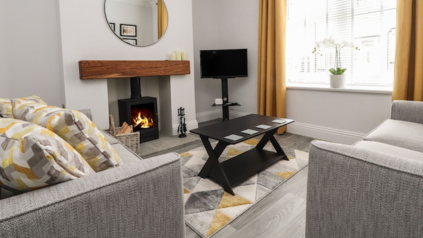 Una sala de estar moderna con chimenea, televisión y un ventanal con cortinas.