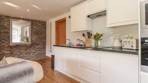 Una cocina moderna con armarios blancos, una puerta de madera y una encimera con un hervidor y una tostadora.