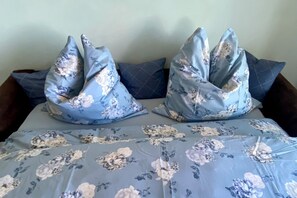 Una cama con ropa de cama y almohadas estampadas con motivos florales.