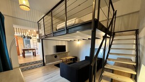 A modern loft-style room with a bunk bed, a flat-screen TV, a dining area, and a staircase. - "Mas Thomasine <br>quiet romantic apartment in nature in Peillon (Peillon)