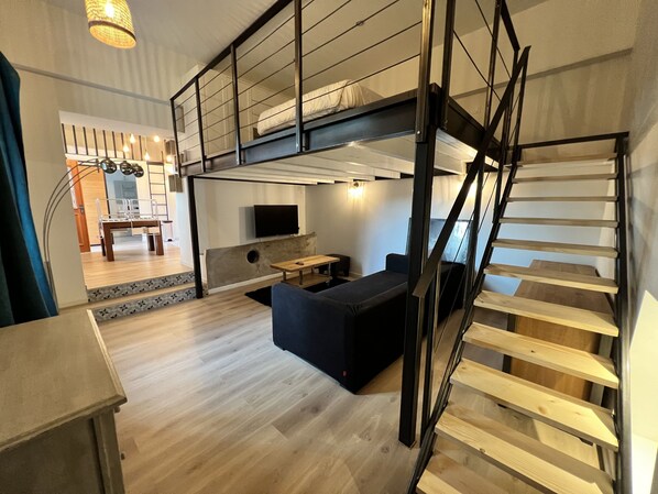 A modern loft-style room with a bunk bed, a flat-screen TV, a dining area, and a staircase. - "Mas Thomasine <br>: a quiet, romantic apartment surrounded by nature in Peillon (Peillon)