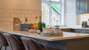 A modern kitchen with a large island, a clock, and a view of the outside. - Upper Sheriff's Place (Windermere)