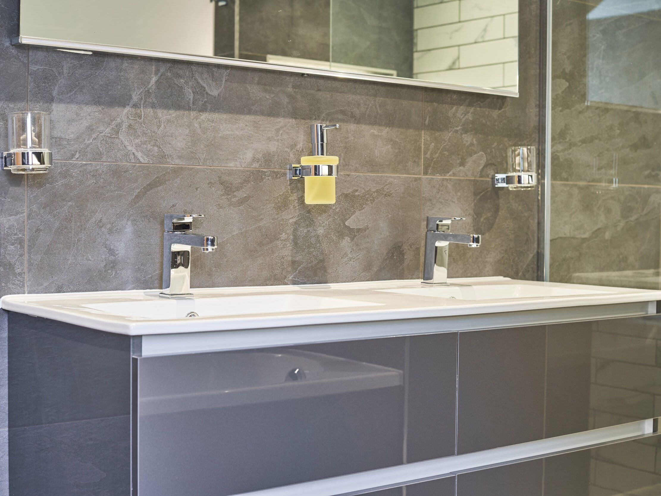 A modern bathroom with a large vanity, two sinks, and a mirror above.