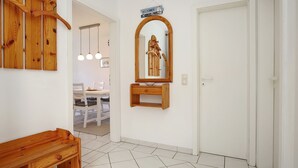 A hallway with a wooden bench, a wooden coat rack, a mirror with a wooden frame, and a welcome sign. - Sünnslag Wohnung 064 (Ostseebad Boltenhagen)