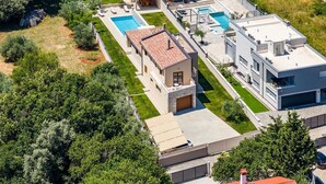 A modern multi-story residential building with a swimming pool, a covered patio, and a garage. - Villa Markulin in village Šišan (Šišan)