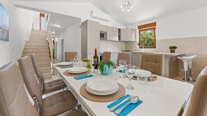 A modern kitchen with a dining area, a staircase, and a view of greenery outside. - Villa Markulin in village Šišan (Šišan)