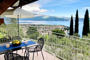 Um terraço com mesa, cadeiras e vista para um lago e uma cidade.