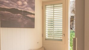 A cozy room with a bed, a window with blinds, and a door leading outside.