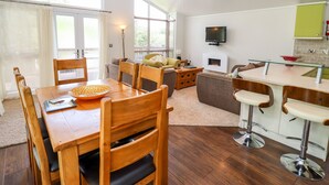 Eine moderne Küche mit Essbereich, einem Fernseher über dem Kamin und einer Bar mit Sitzgelegenheiten.