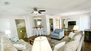 A living room with a sofa set, a coffee table, a lamp, a ceiling fan, and a TV.