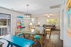 A spacious living area with a glass dining table, wicker chairs, a sofa, and a ceiling fan. - 5 Blocks 2 Beach-Pet Friendly- Golf Cart-Early Check-in (North Myrtle Beach)