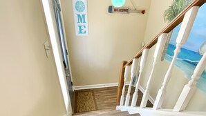 A wooden staircase with white railings and a 'Welcome Home' sign on the wall.