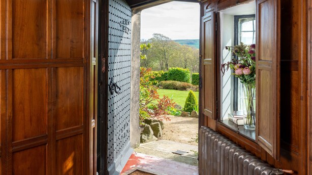 A wooden door opening to a garden with a view of trees and a clear sky. - Fernhill Castle (Keighley)