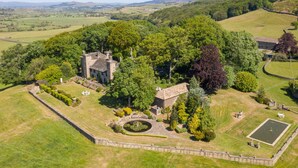 An aerial view of a historic estate with a large stone manor, manicured gardens, and a moat. - Fernhill Castle (Keighley)