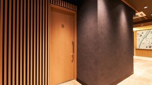 A wooden door with a small emblem, a dark wall, and a tiled floor. - Rakuten STAY Tokyo Asakusa (Tokyo)