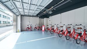 A bike-sharing station with multiple red bicycles and a sheltered area with a clear path marked for sharing. - Rakuten STAY Tokyo Asakusa (Tokyo)