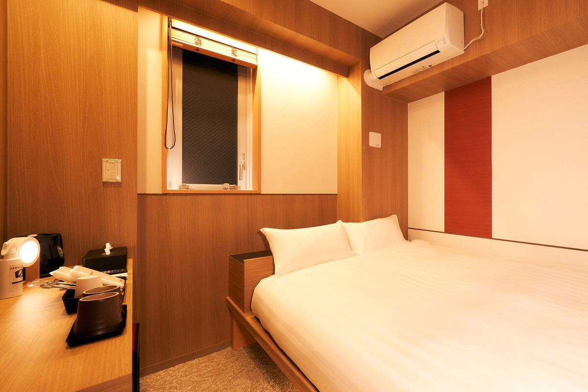 Une chambre d’hôtel équipée d’un lit, d’une table de chevet, d’une lampe et d’un appareil de climatisation.