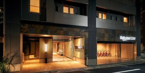 Entrada de hotel con diseño moderno, recepción a la vista y zona de aparcamiento para bicicletas.
