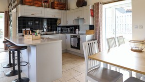 A modern kitchen with white cabinets, a central island, and bar stools.