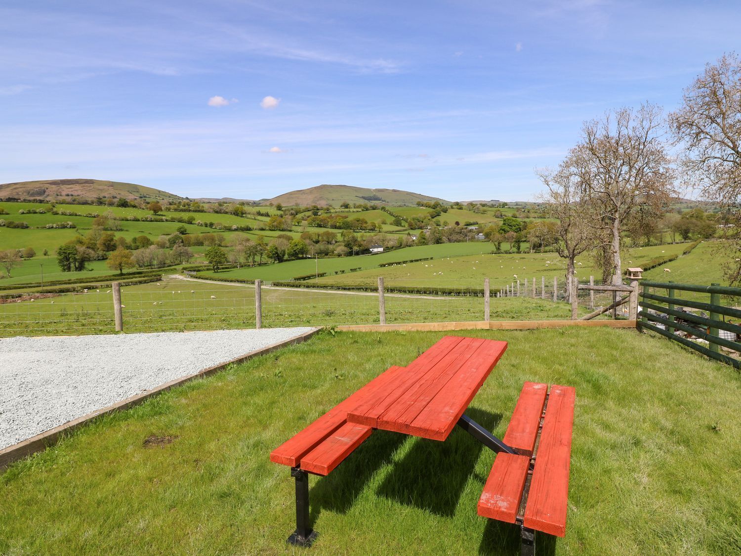 A picnic table in a grassy area with a view of rolling hills and a clear sky.