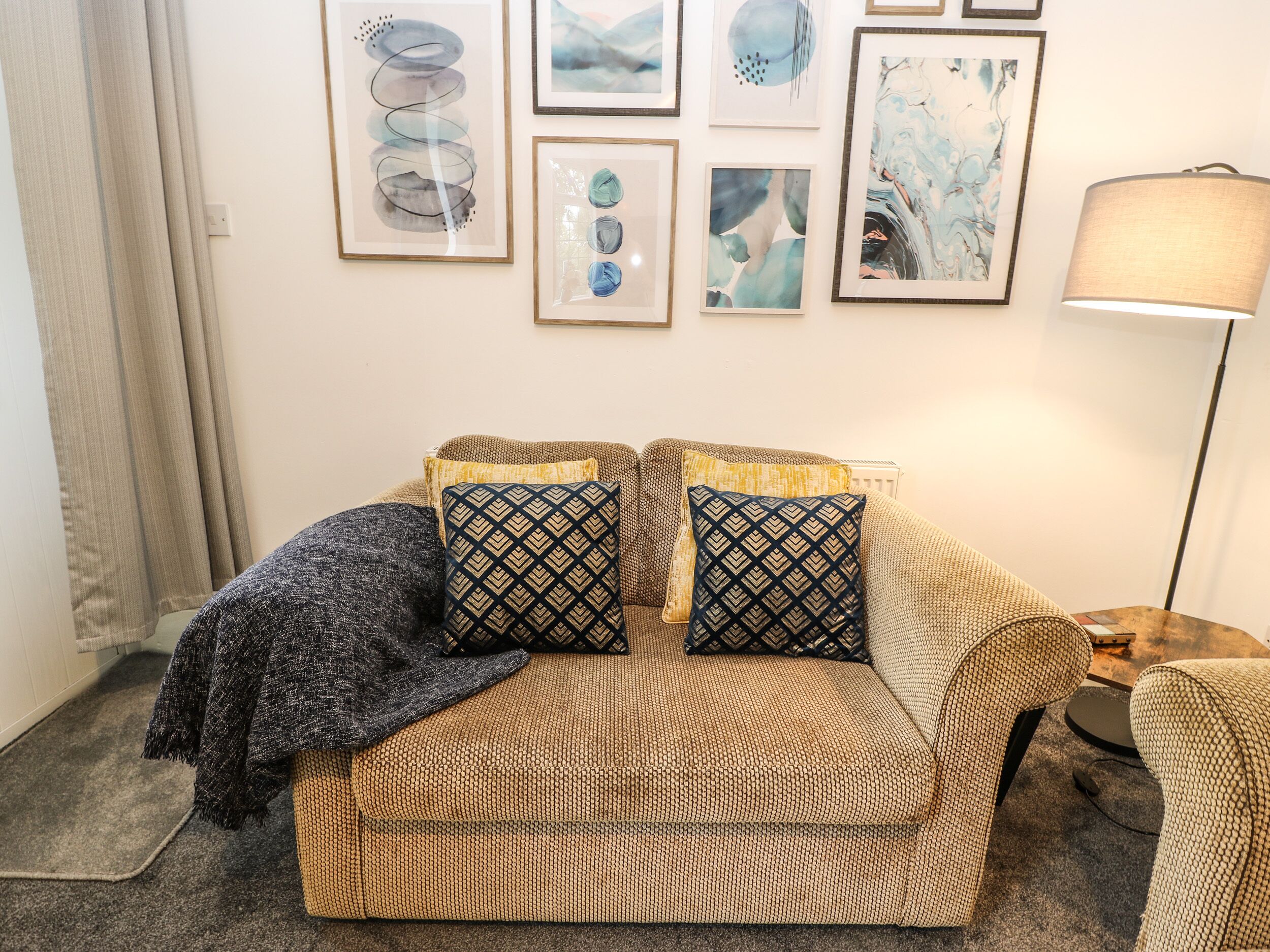 A cozy living room with a patterned sofa, two patterned throw pillows, and a floor lamp.
