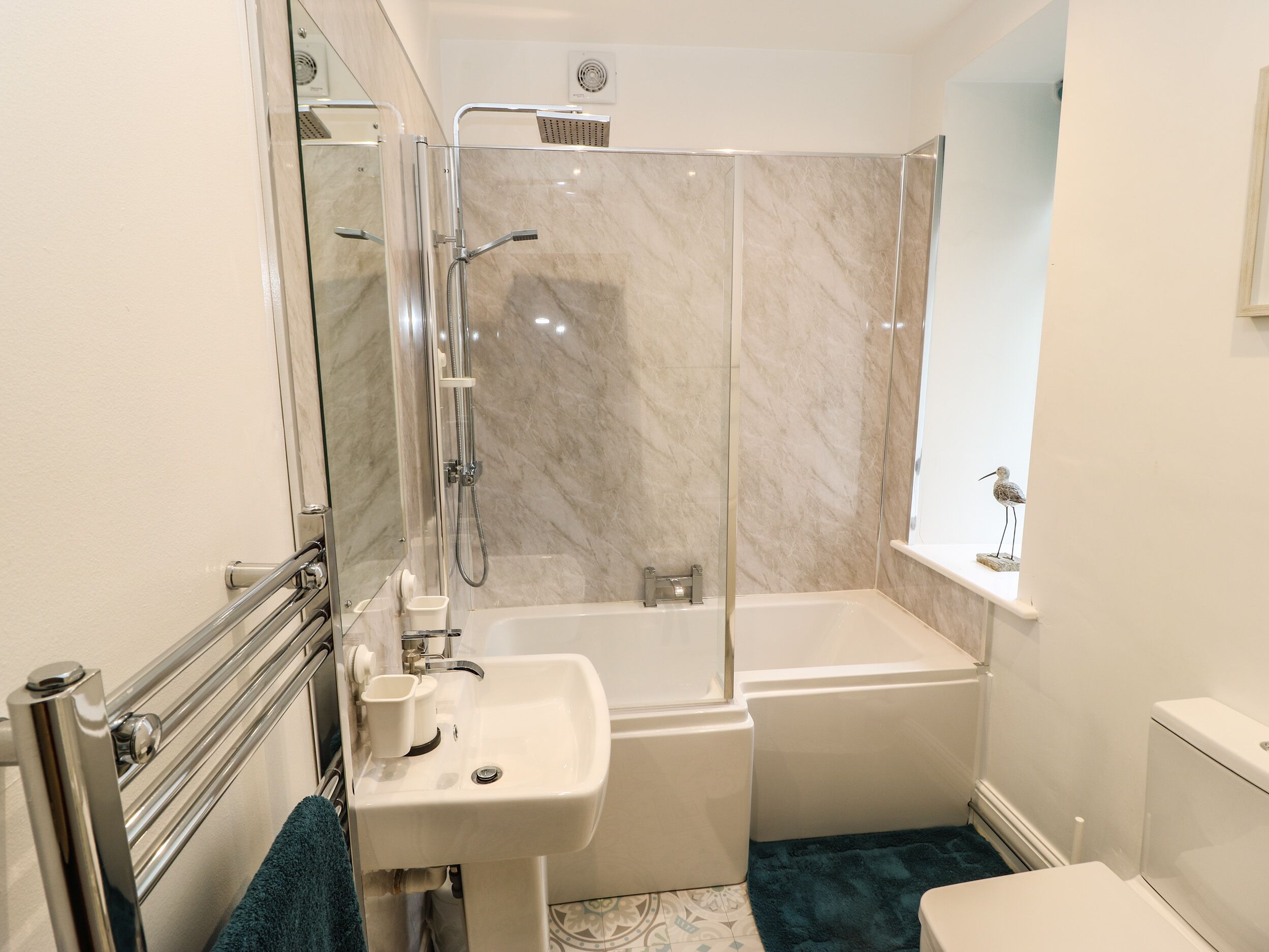 Un baño moderno con ducha acristalada, lavamanos blanco y bañera.